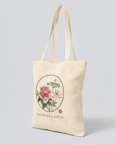 Beige Tragetasche aus hochwertiger Baumwolle mit einer runden Illustration von rosafarbenen Pfingstrosen und Lotusblüten im asiatischen Stil, inklusive dem Schriftzug „The Peony & Lotus“