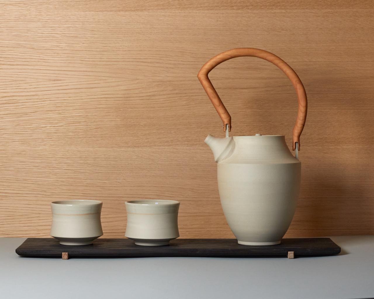 Langes handgefertigtes Holztablett mit der Kanne Air und zwei Teetassen von Moritz Frohnhöfer, minimalistische Präsentation auf hellem Hintergrund.